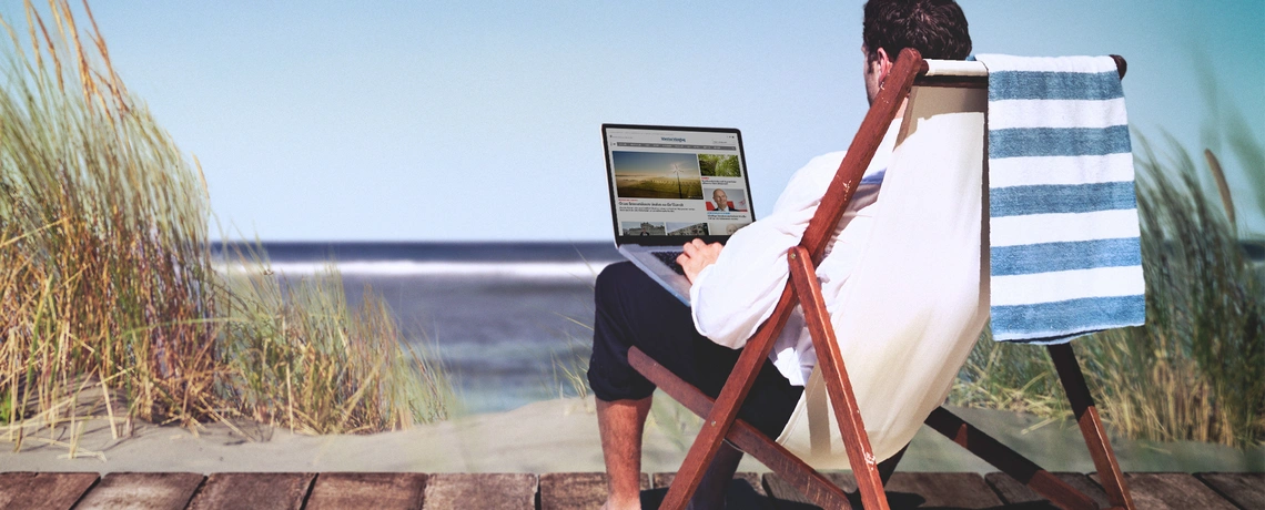 Mann liest digitale Tageszeitung am Meer