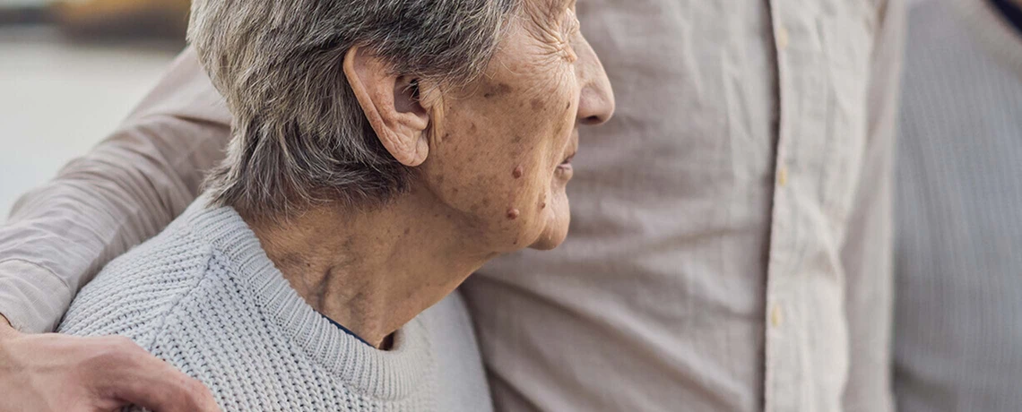 Sohn hält schützend seinen Arm um die Schulter seiner Mutter