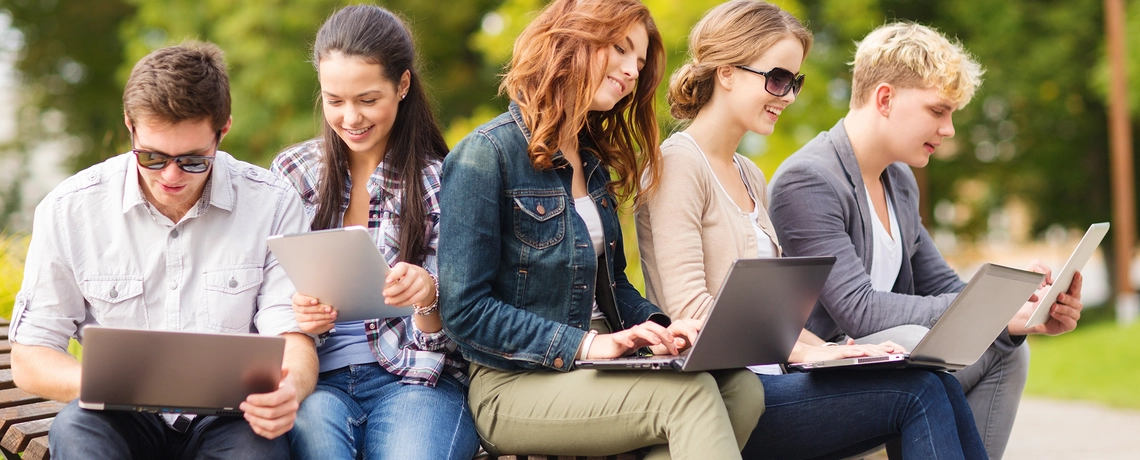 Junge Menschen in der Schule, die am Laptop oder am Tablet sitzen